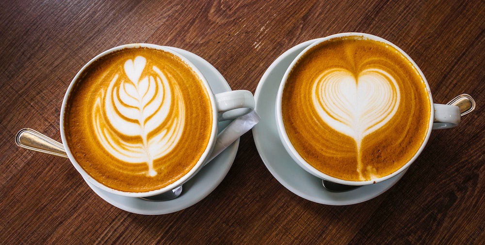 coffee mugs with latte art in the shape of a heart